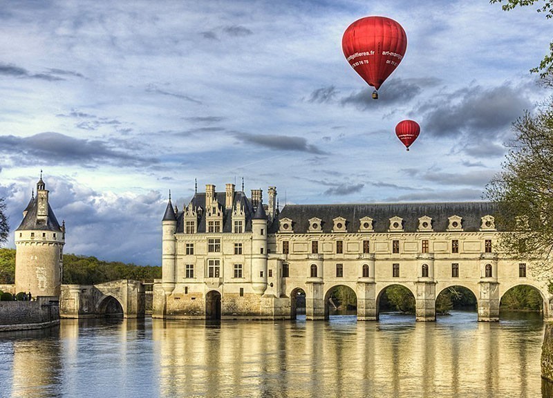 Two red hot air balloons fly above the Chenonceau Castle spanning the river Cher in Chenonceaux, Loire Valley | 10 Best Hot Air Balloon Rides Around The World